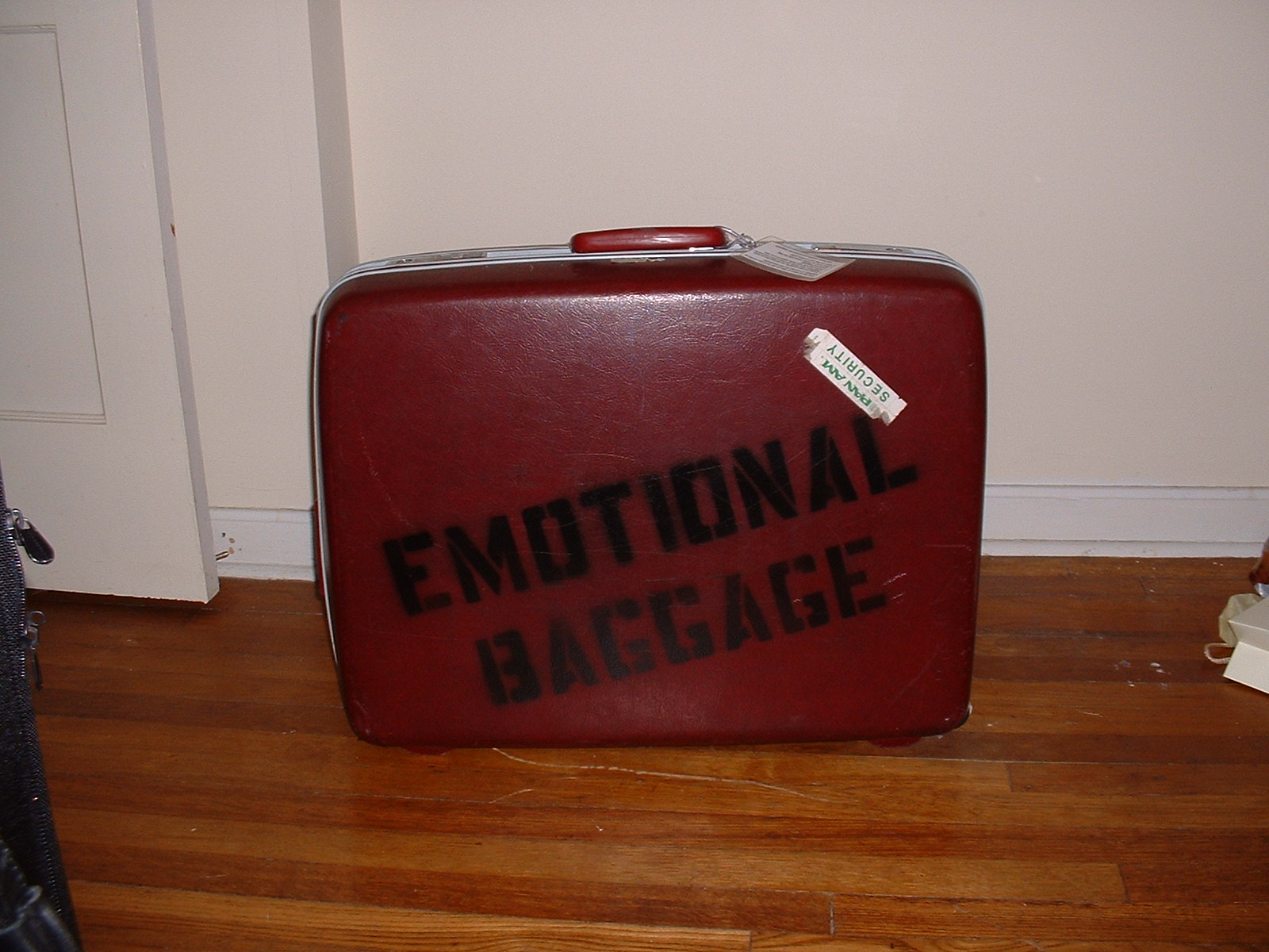 Image: Retro red suitcase with 'Emotional Baggage' stenciled on side.